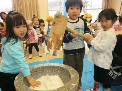 保育所の部屋の中で男の子1名と女の子2名が餅つきをしている写真